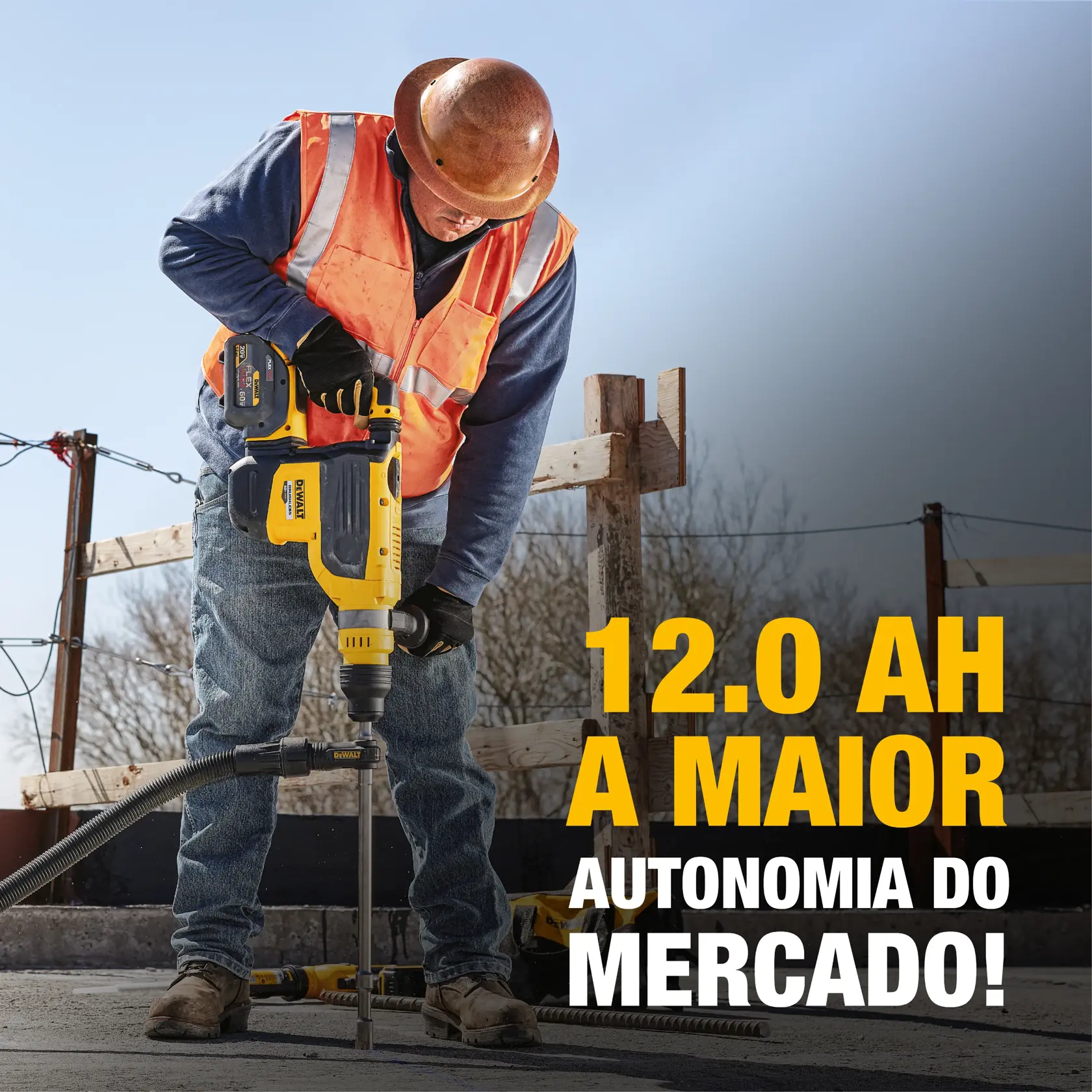 Um trabalhador da construção civil usando capacete e colete de segurança utiliza uma ferramenta elétrica DEWALT para perfurar concreto em um canteiro de obras. A Estátua da Liberdade e uma bandeira americana são visíveis ao fundo.