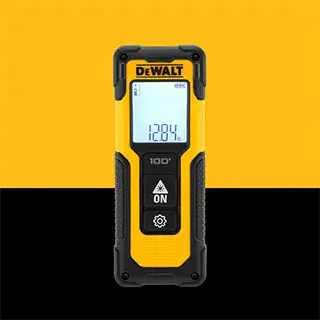 Uma pessoa usando colete de segurança, luvas de trabalho e capacete está utilizando um medidor de distância a laser DEWALT para medir a largura de tábuas de madeira em um local de construção. O rosto da pessoa está desfocado para privacidade.