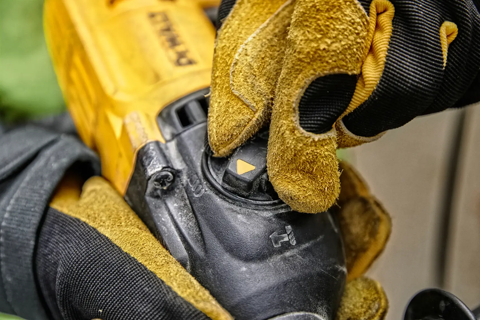 Close-up de uma mão com luva ajustando o seletor de modo em uma ferramenta elétrica amarela DEWALT.