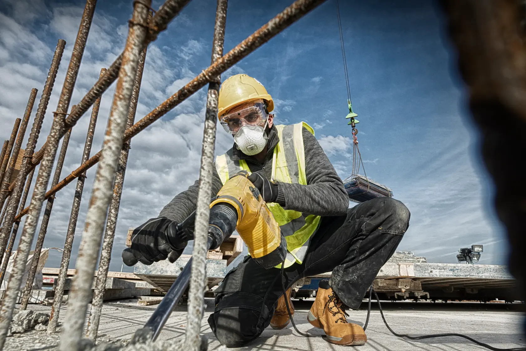 DEWALT D25481K, D25481 martelete utilizado em obra; trabalhador perfura concreto entre vergalhões.