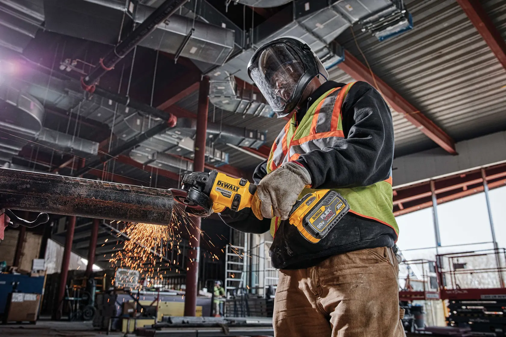 Trabalhador usa bateria DEWALT DCB609 em ferramenta elétrica cortando tubo metálico com faíscas no local industrial.