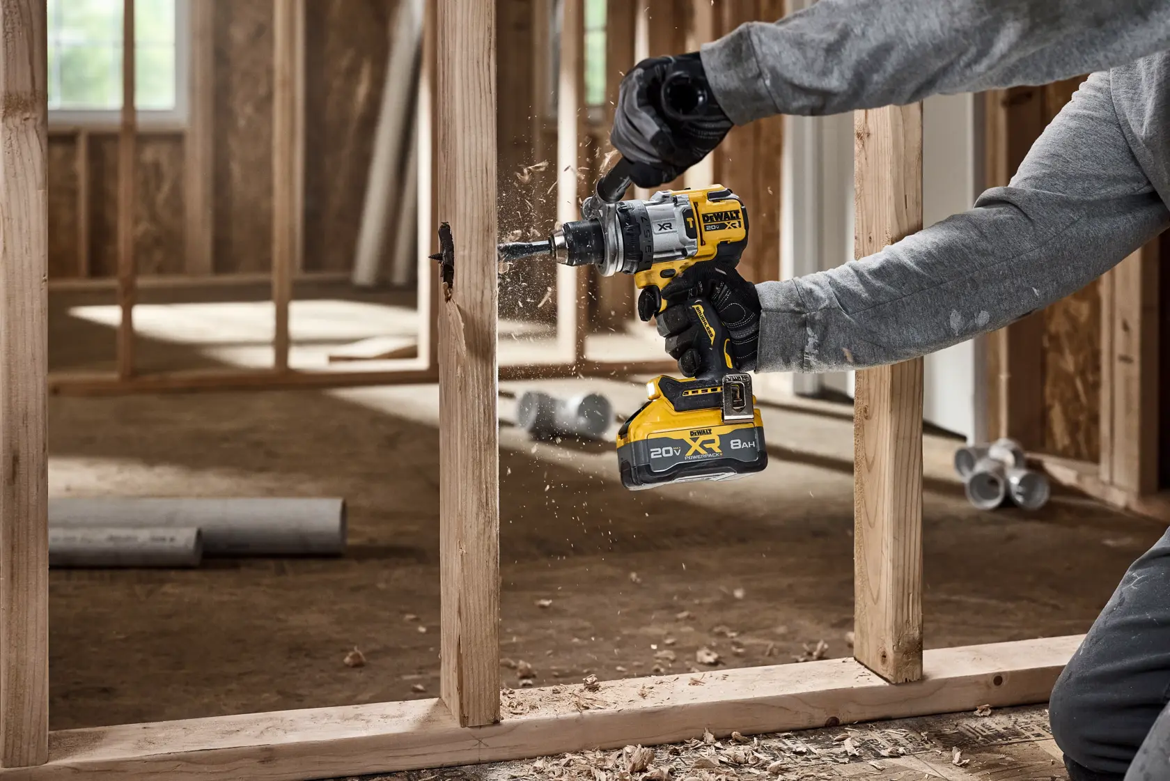 Persona usa un taladro inalámbrico DEWALT para cortar un agujero en un piso de madera en construcción.