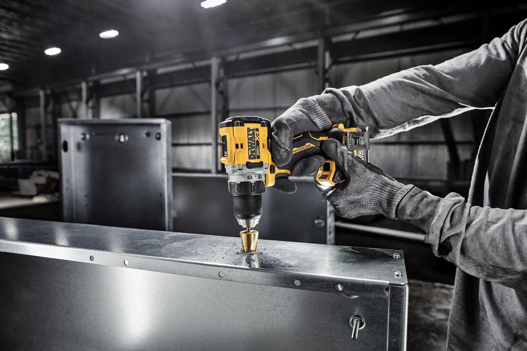 Uma pessoa com luvas usa uma furadeira sem fio DEWALT para fazer um furo em uma chapa de metal em um ambiente industrial.