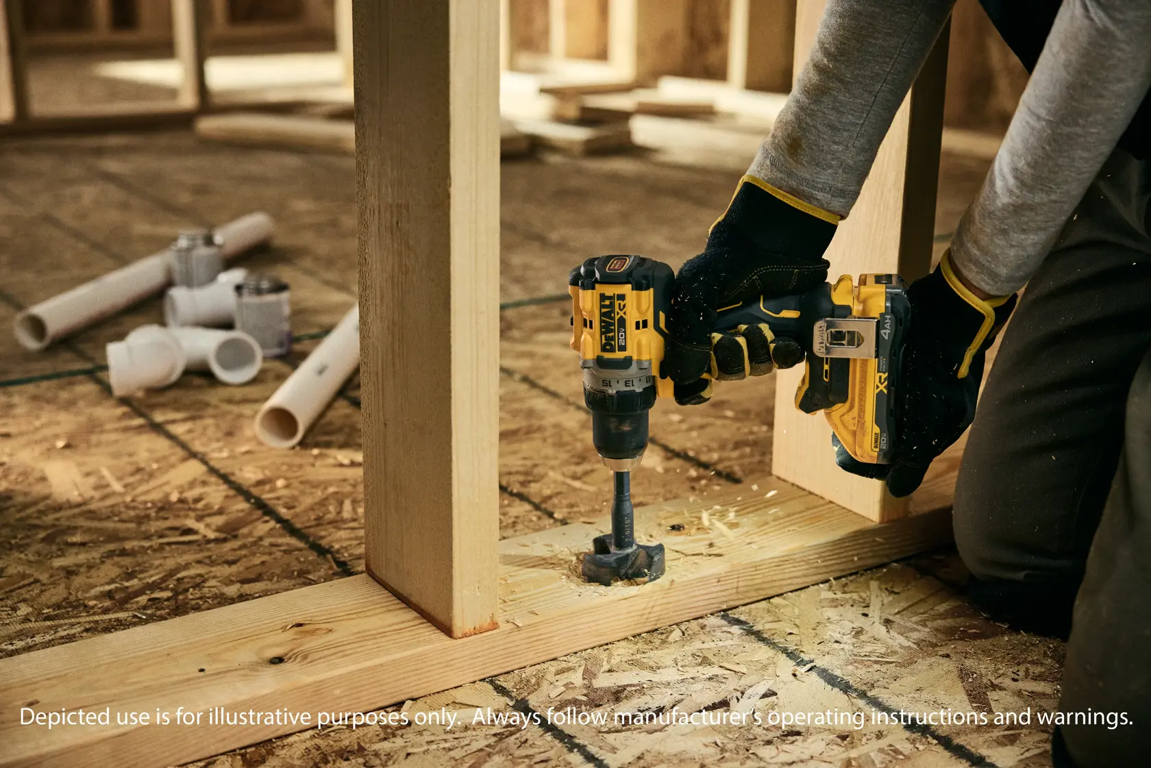 Uma pessoa usando luvas de trabalho está usando uma furadeira sem fio DEWALT para perfurar um buraco em uma superfície de metal, com uma parede de concreto ao fundo.