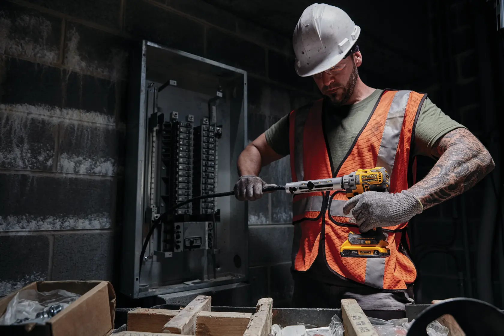 Um trabalhador usa uma ferramenta de decapagem de cabos sem fio DEWALT 20V Max com buchas de liberação rápida para remover o isolamento de um cabo elétrico grosso. A ferramenta é segurada por uma mão com luva, e o trabalhador veste um colete de segurança refletivo. O texto destaca as buchas de liberação rápida como ideais para vários tamanhos de cabos.