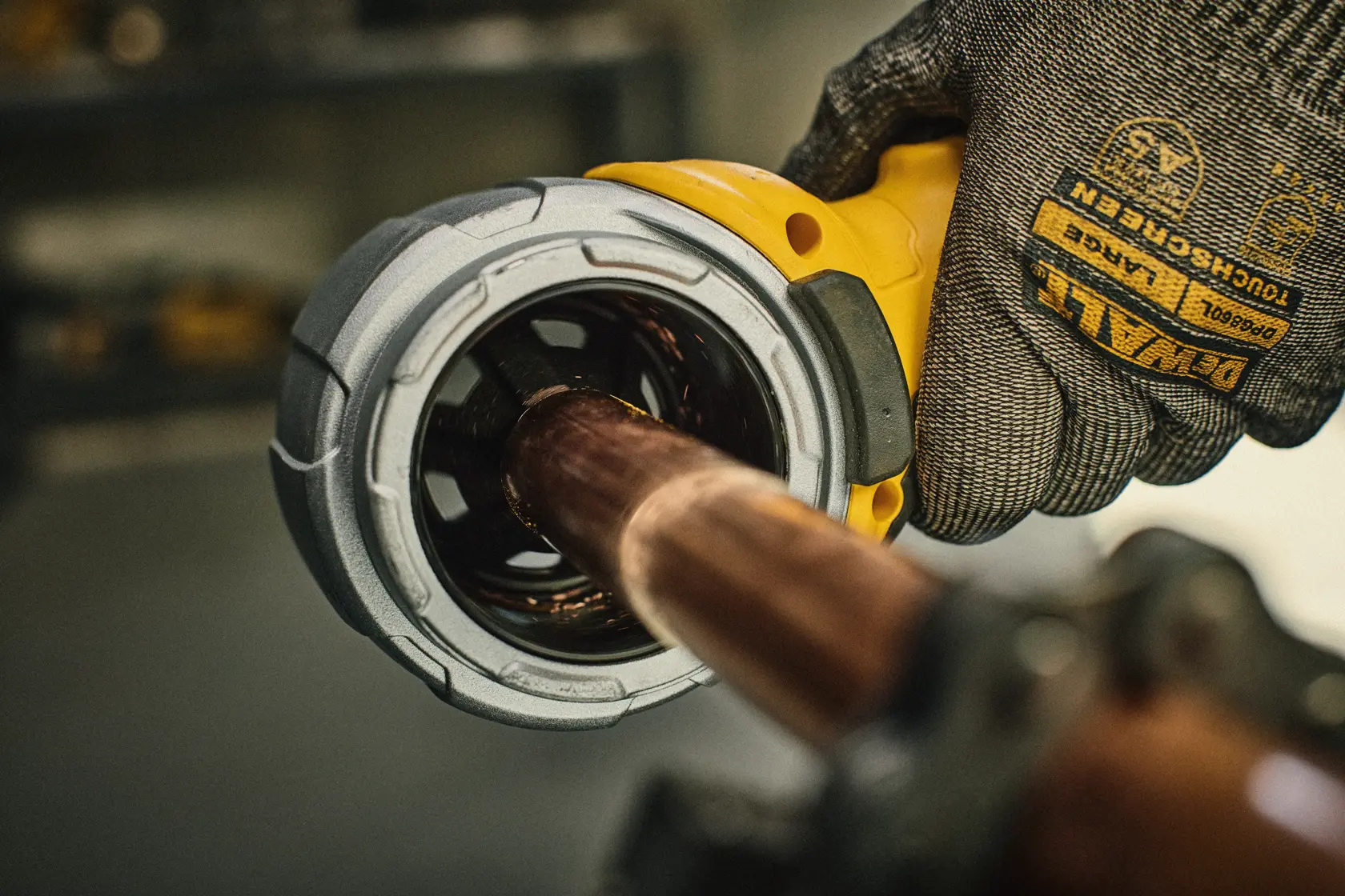 Close de uma pessoa usando luvas da marca DEWALT utilizando uma ferramenta DEWALT para rebarbar a extremidade de um tubo de cobre. O texto na imagem destaca a função de dupla rebarbação da ferramenta para as bordas internas e externas.