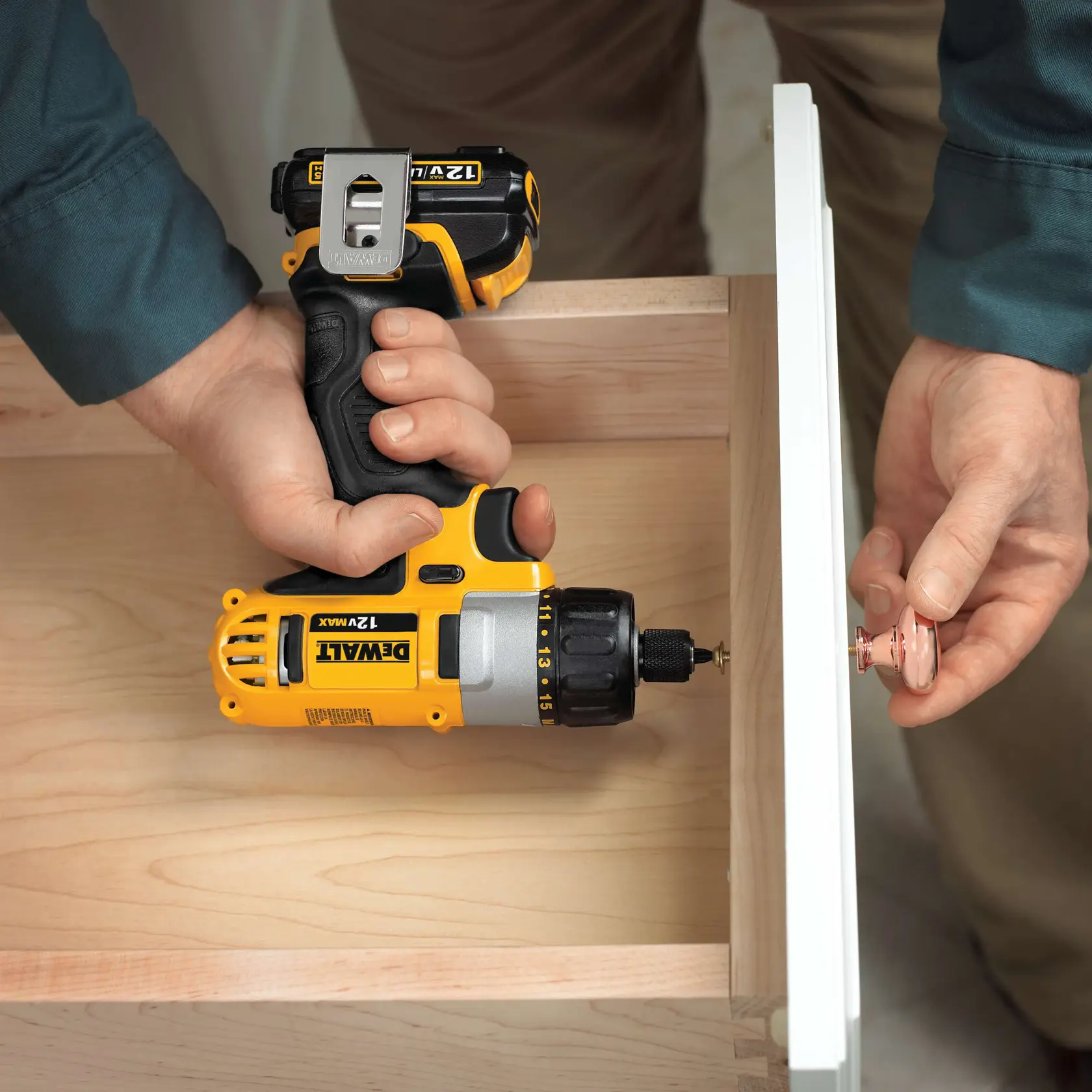 Uma pessoa utiliza uma furadeira sem fio DEWALT 12V Max para instalar um puxador em uma gaveta de madeira.