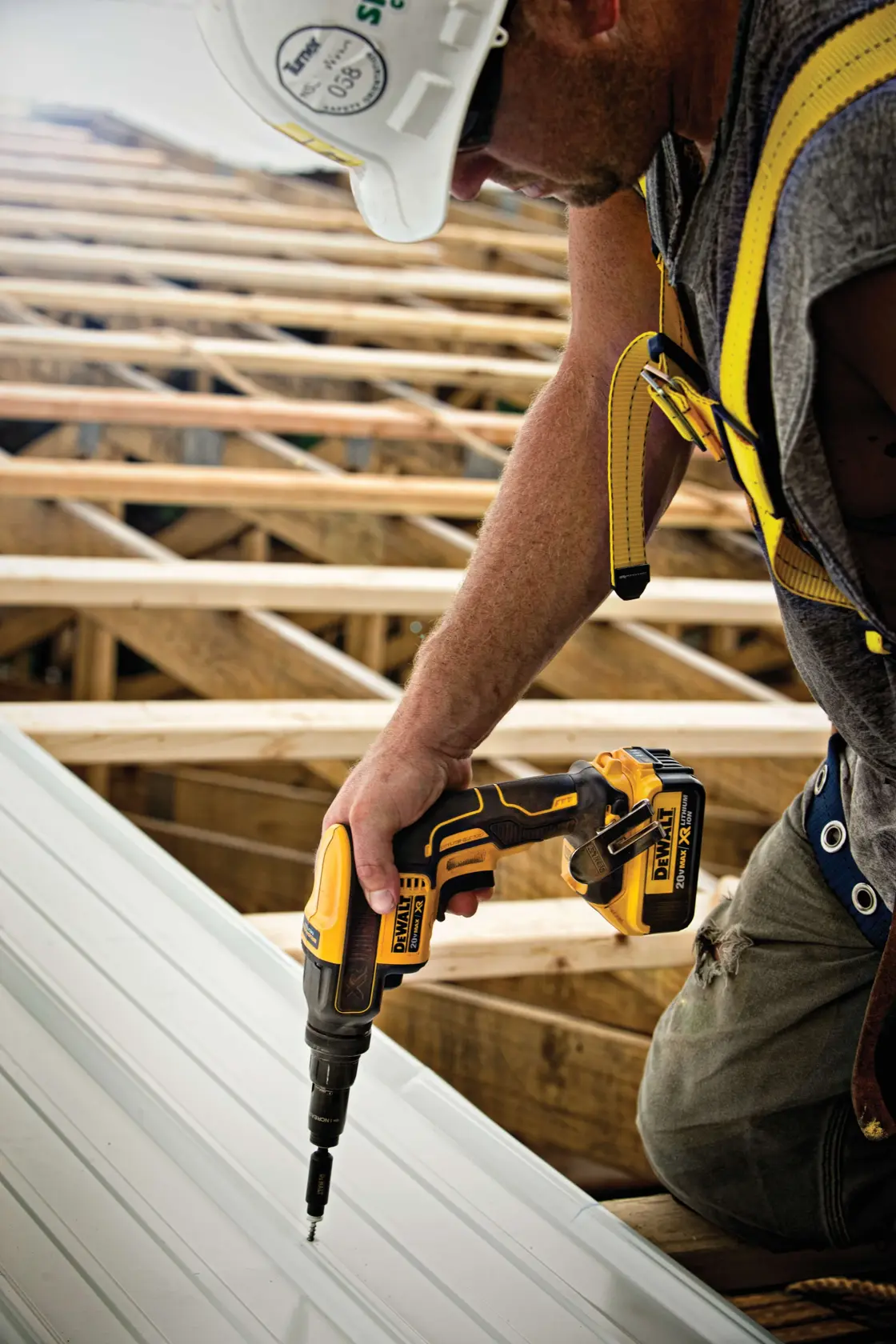Uma mão com luva segurando uma parafusadeira sem fio DEWALT (SKU: DCF622B) com sistema Versa-Clutch, sendo usada em uma superfície metálica em uma oficina. O texto promocional destaca a prevenção de danos a materiais e fixadores.