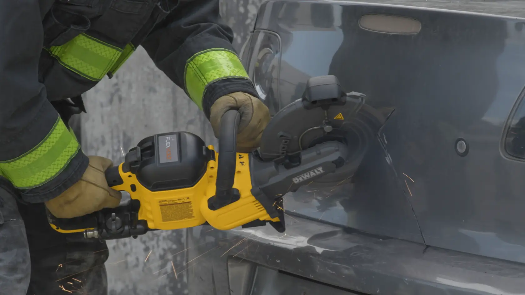 Uma pessoa usando luvas de proteção está utilizando uma serra de corte sem fio amarela DEWALT para cortar a lataria metálica de um veículo, gerando faíscas.