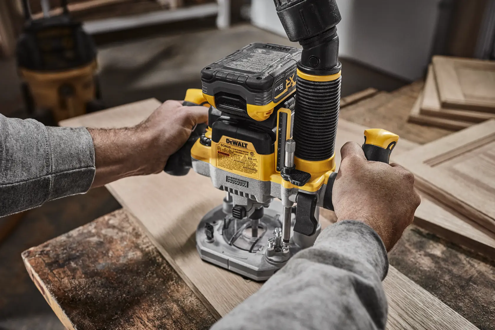 Uma pessoa utiliza uma roteadora sem fio DEWALT XR (modelo DCW620B) em uma tábua de madeira. O texto destaca que a roteadora pode completar até 256 pés lineares de funcionamento por carga. A bateria é vendida separadamente.