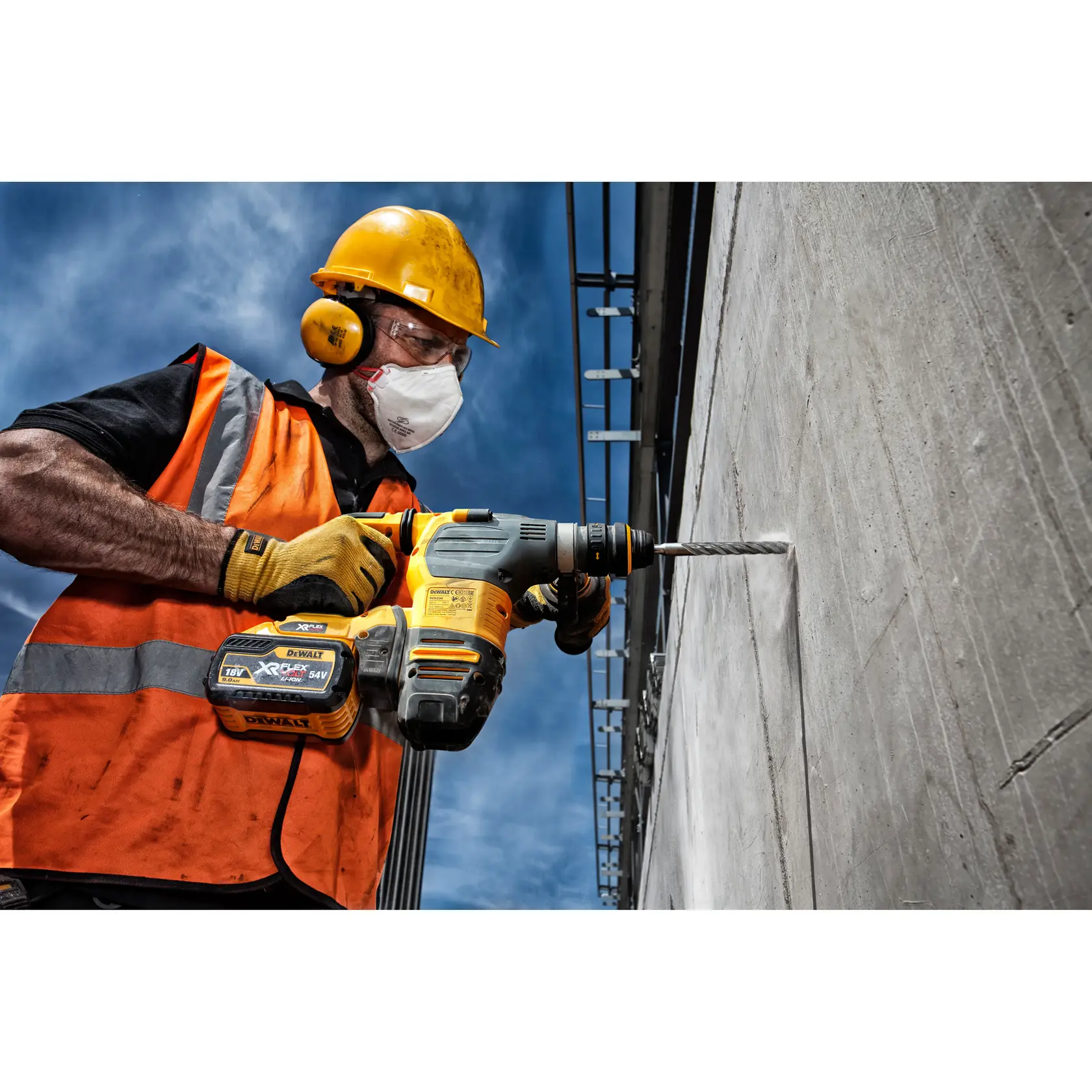 Trabalhador perfura parede de concreto com martelete DEWALT e broca DT9502. Usa capacete, luvas, colete.