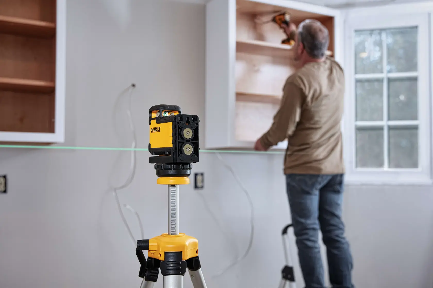 Ferramenta de nível a laser DEWALT com corpo amarelo e preto, apresentando partes identificadas como painel de controle touch, suporte magnético integrado, pêndulo de bloqueio, interruptor de trava em três posições com modo manual e feixe verde para visibilidade e alcance aprimorados.