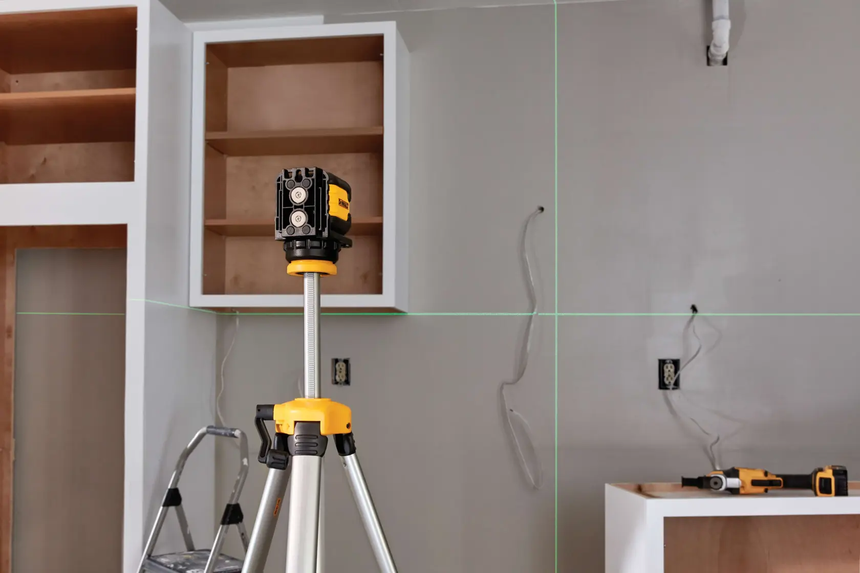 Kit de nível laser de linha cruzada verde DEWALT DW08802CG exibido aberto. Dentro do estojo moldado estão o nível laser de linha cruzada verde, duas pilhas AA e outros acessórios, incluindo um suporte de teto. Uma lista de produtos detalhando o conteúdo aparece acima do estojo.