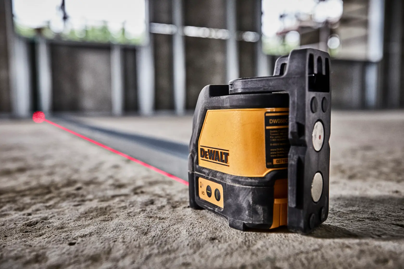 Kit de nível a laser de linhas cruzadas DEWALT DW088K, incluindo uma maleta de transporte rígida preta com o logotipo amarelo da DEWALT, um nível a laser de linhas cruzadas amarelo e preto, três pilhas AA e um suporte de teto preto, organizados juntos sobre uma superfície cinza clara.