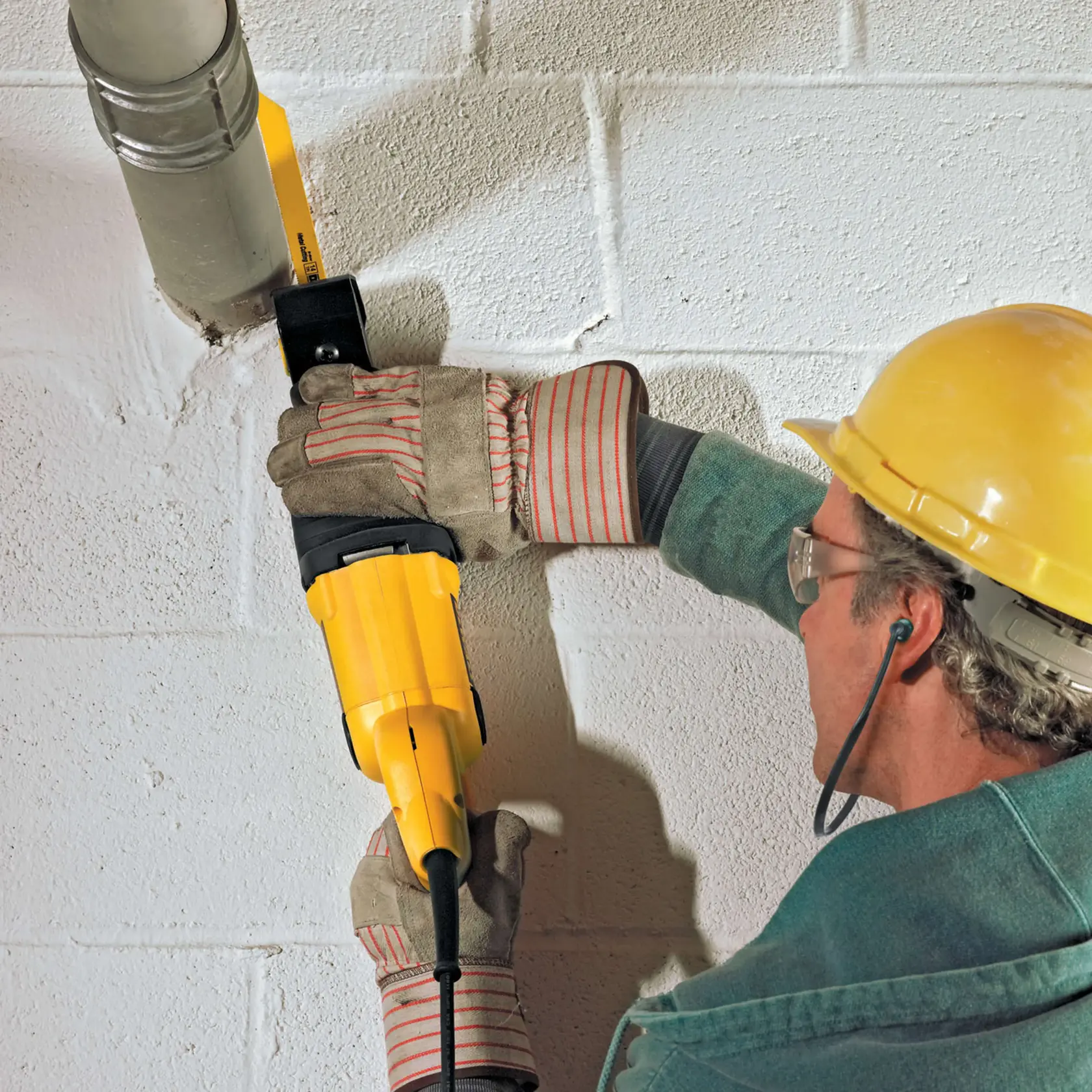 Foto de trabalhador usando serra sabre DEWALT DW304PK para cortar tubo, com luvas e capacete.