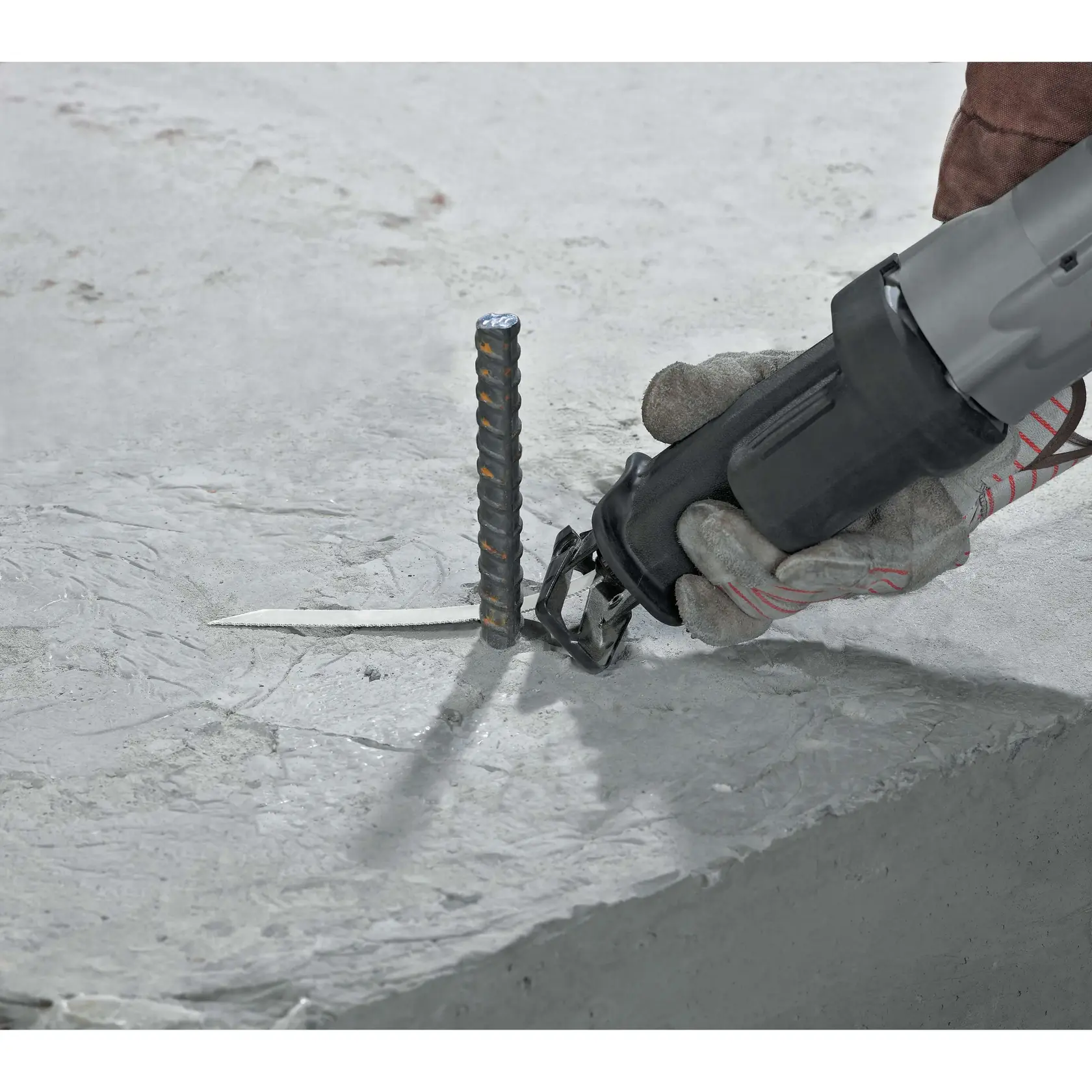 Foto da serra DEWALT DW304PK cortando vergalhão em concreto, close da ferramenta e luva, fotografia.