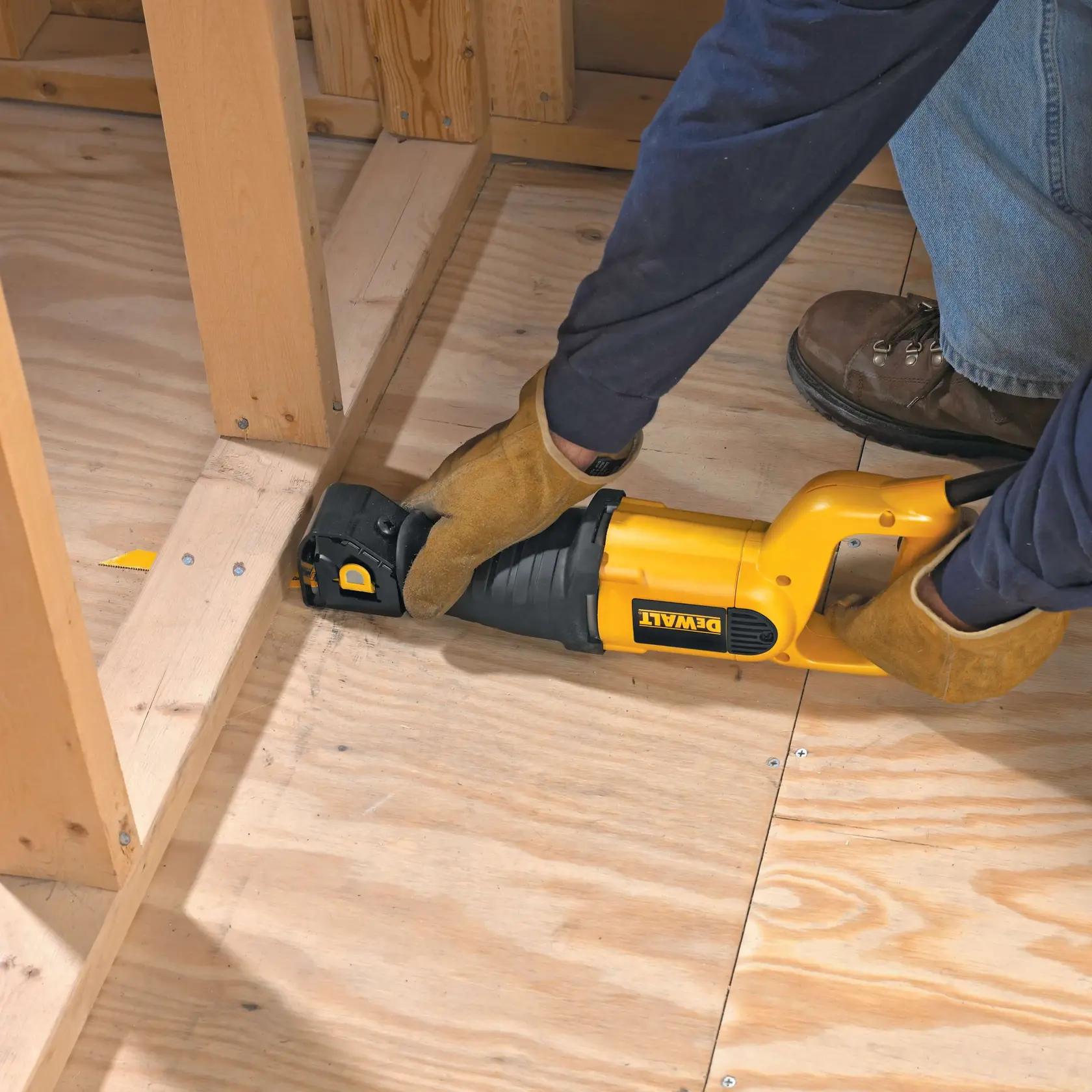 Fotografia da serra reciprocante DEWALT DW304PK cortando piso de madeira, ferramenta amarela e preta com luvas.