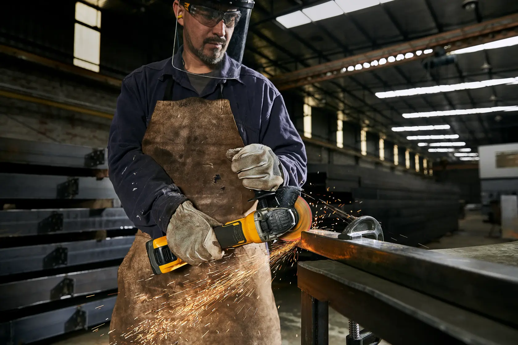 Operário usa esmerilhadeira DEWALT em metal, soltando faíscas e usando equipamento de proteção.