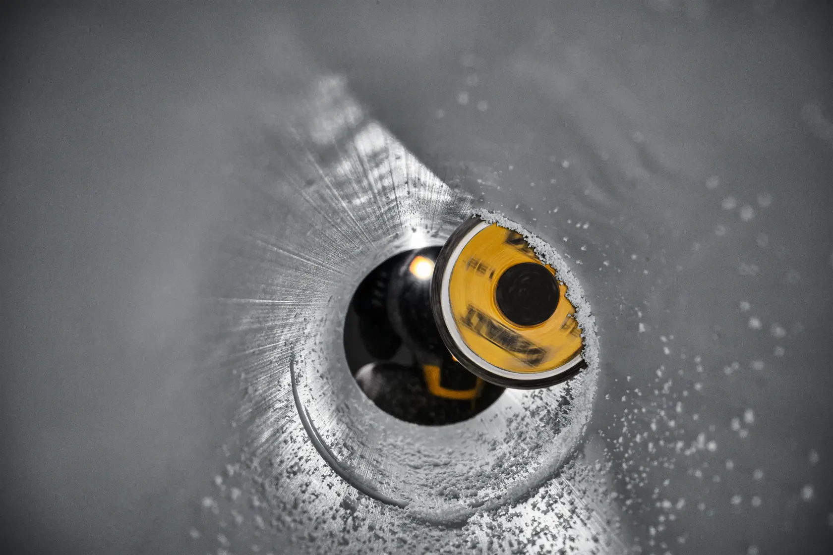 Close de uma ferramenta elétrica DEWALT sendo usada com um barril anodizado preto dentro de um encaixe de metal corroído, destacando a resistência à corrosão e proteção contra ferrugem.