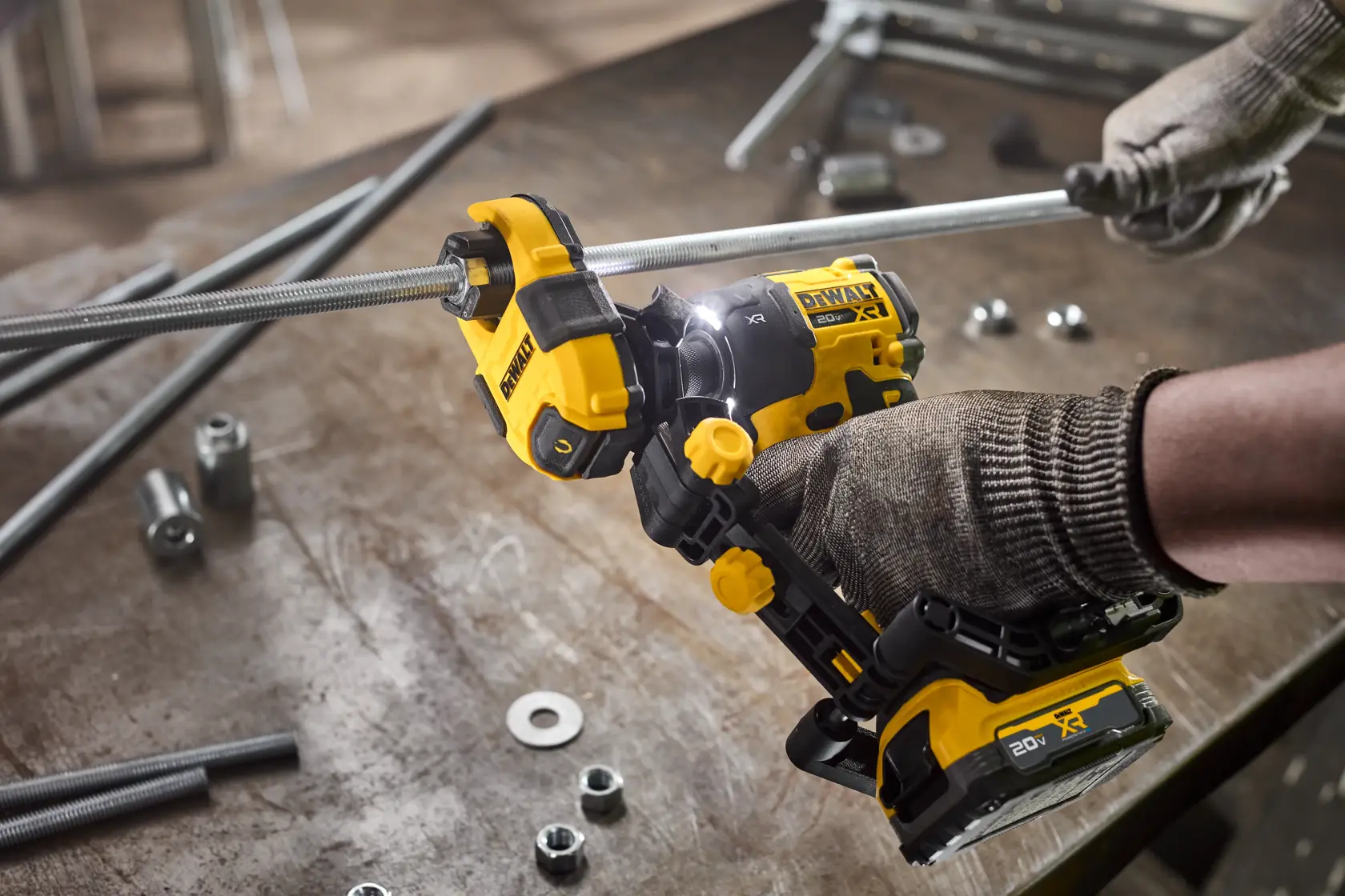 Uma ferramenta de elevação DEWALT está sendo usada para levantar tubos de metal com uma barra roscada, mostrando capacidade de elevação de até 100 lbs (45,4 kg). O rosto do trabalhador está desfocado e a capacidade de elevação é destacada no texto. A imagem observa que o parafusador de impacto é vendido separadamente.