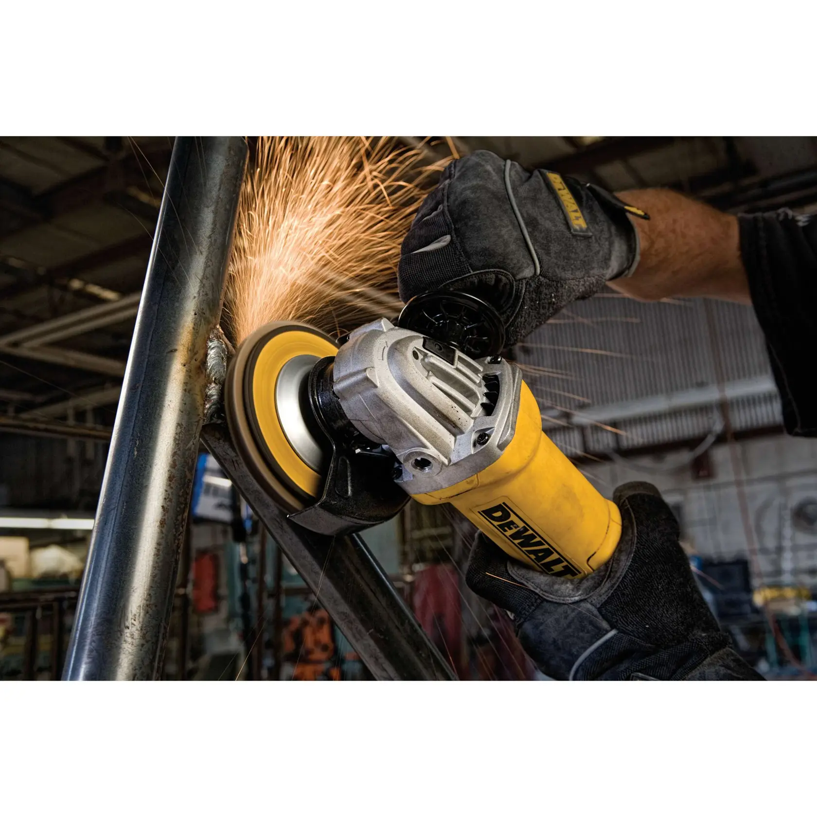 Imagem em close-up de uma esmerilhadeira angular DEWALT sendo usada em um tubo de metal, com faíscas voando enquanto a ferramenta lixa a superfície. A pessoa operando a ferramenta está usando luvas de proteção e a cena ocorre em uma oficina industrial.
