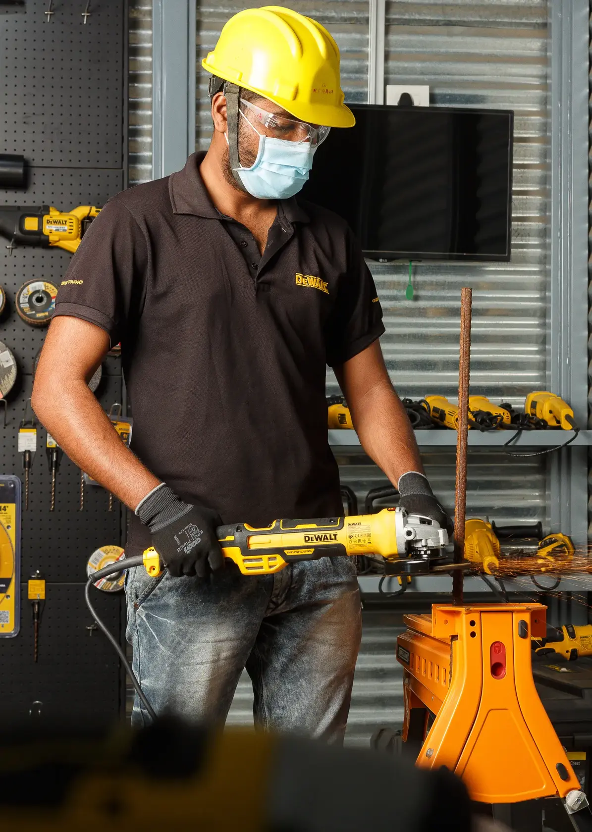 Foto de operário usando esmerilhadeira DEWALT DWE4377 em barra de metal, com EPI em oficina.