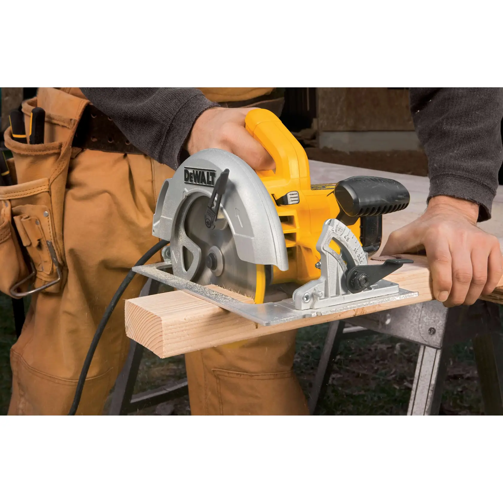 Uma pessoa está usando uma serra circular DEWALT DWE575 para cortar um pedaço de madeira em uma bancada. A serra é amarela e prateada e está conectada por um cabo. A pessoa está vestindo roupas de trabalho.