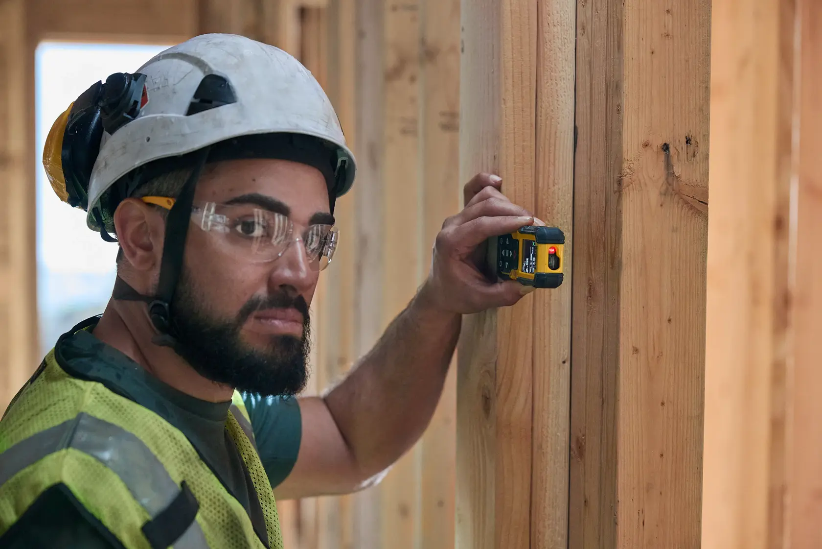 Ferramenta eletrônica de medição portátil DEWALT DWHT77200 exibida na posição vertical, com etiquetas destacando características como longo alcance, visibilidade clara, facilidade de uso, operação versátil, alta precisão e operação conveniente. O dispositivo possui uma tela e vários botões de controle.