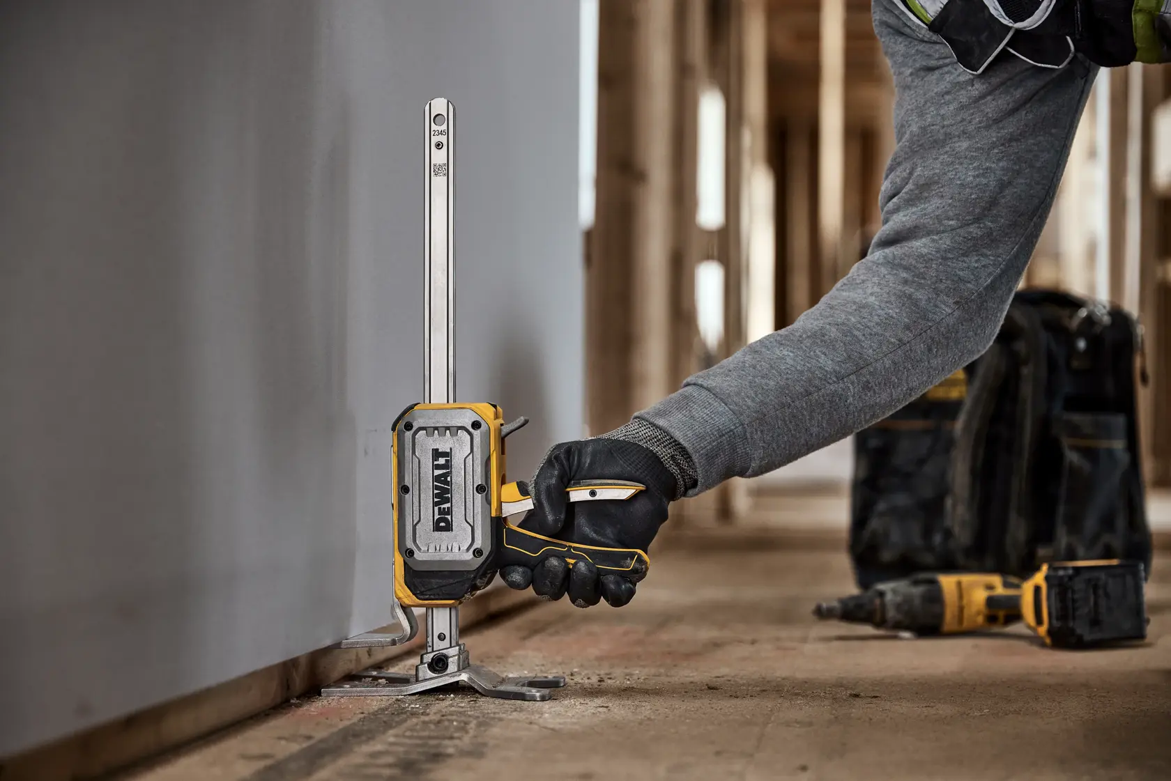 Uma mão com luva opera uma ferramenta DEWALT DWHT83550 com botão de liberação rápida próximo a uma moldura de janela. A ferramenta está posicionada para aplicação precisa, e o texto destaca a função de liberação rápida sem carga.