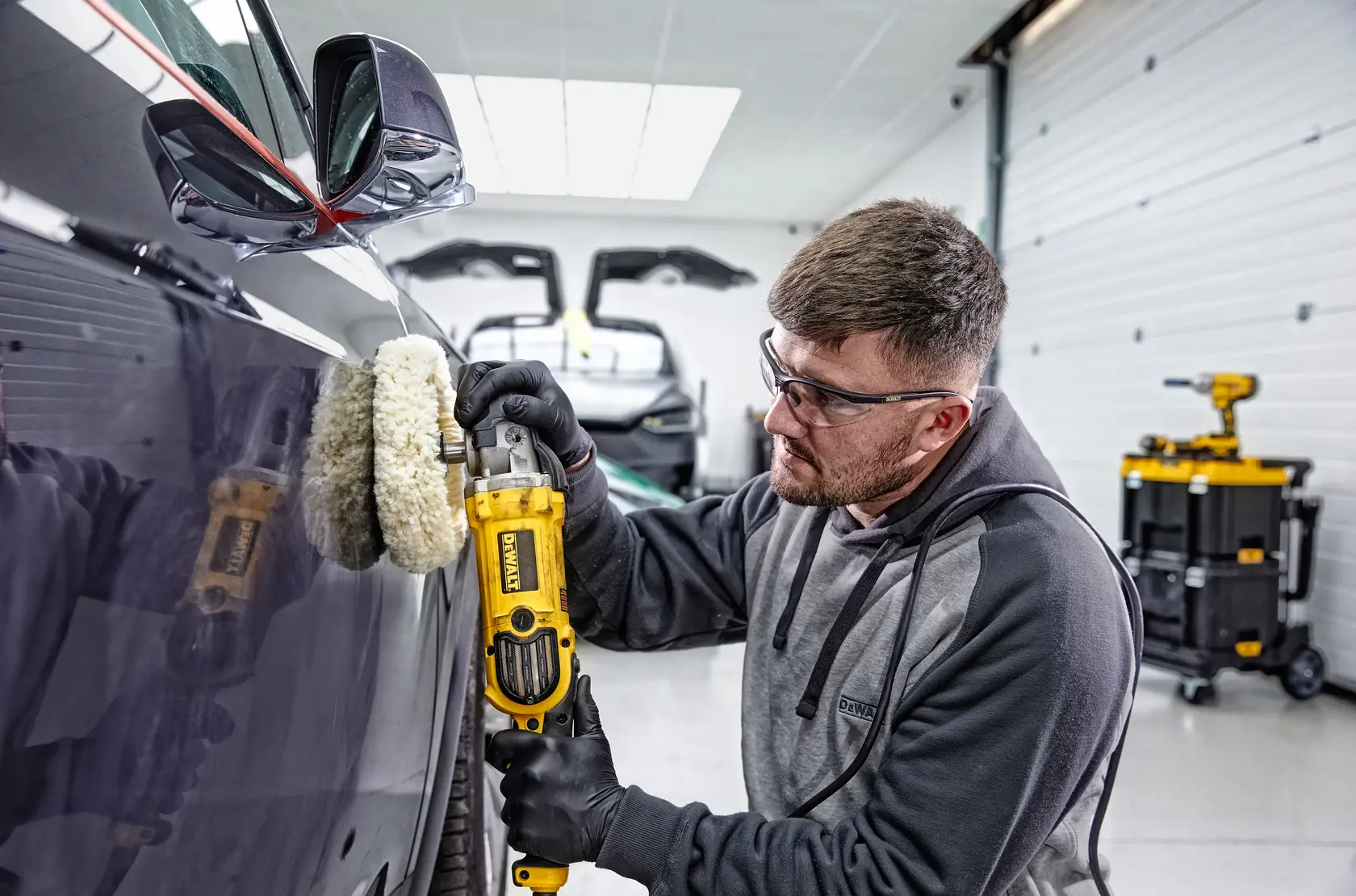 Photo of person using DEWALT polisher DWP849X-B2, DWP849XB2, DWP849X-B3, DWP849X, DWP849X-AR on car in garage.