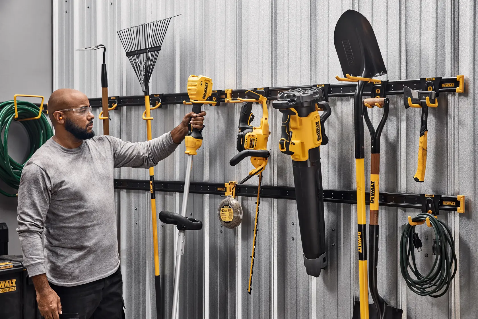 Gráfico do sistema de armazenamento de oficina personalizável DEWALT mostrando um trilho de armazenamento metálico preto horizontal com terminações amarelas.