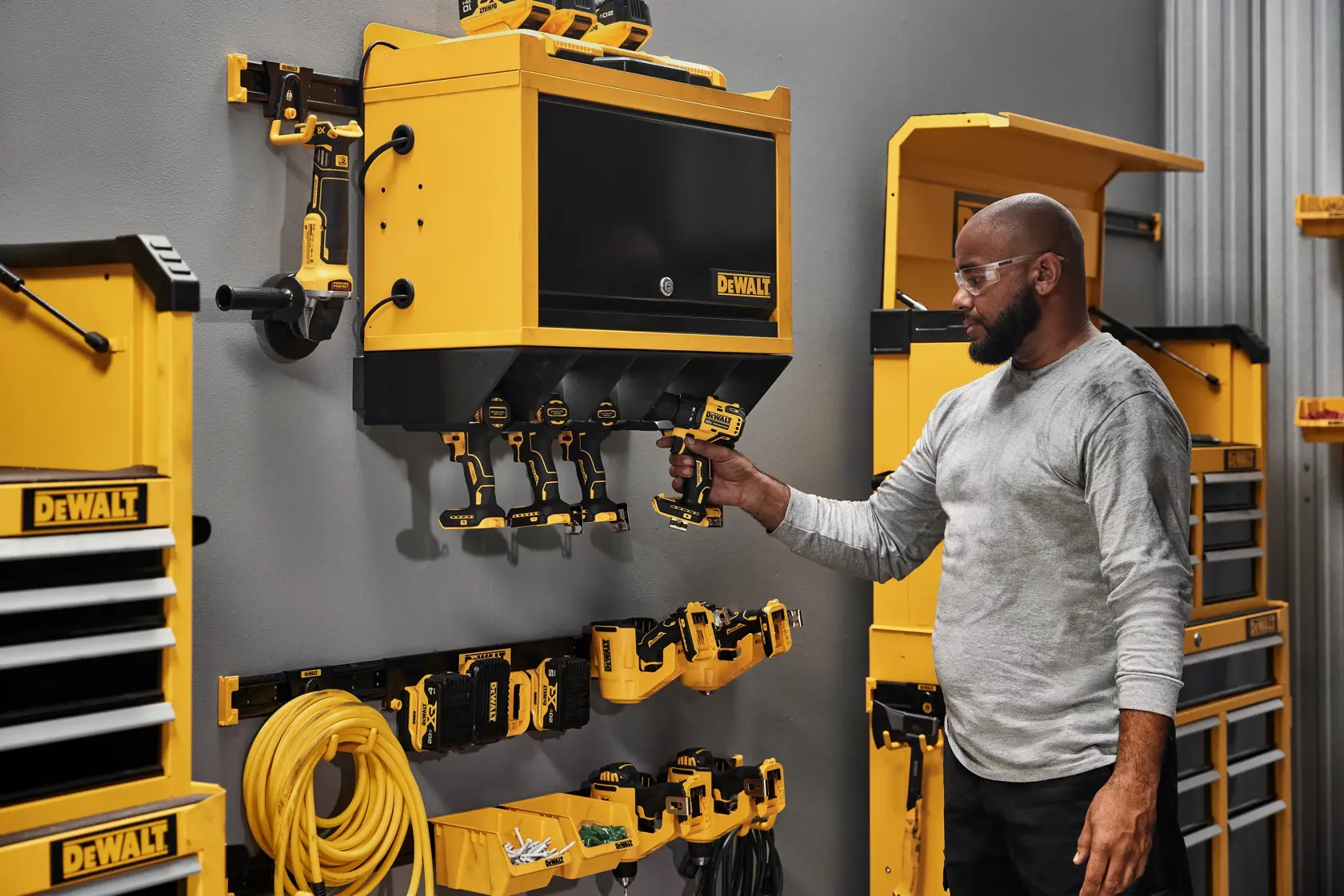 Imagem com dois recipientes de armazenamento amarelos DEWALT lado a lado, parte de um sistema de armazenamento personalizável para oficina. Os recipientes apresentam o logotipo DEWALT e um símbolo de capacidade de peso. Acima dos recipientes há uma faixa amarela com texto preto que diz 'CUSTOMIZABLE WORKSHOP STORAGE SYSTEM.'